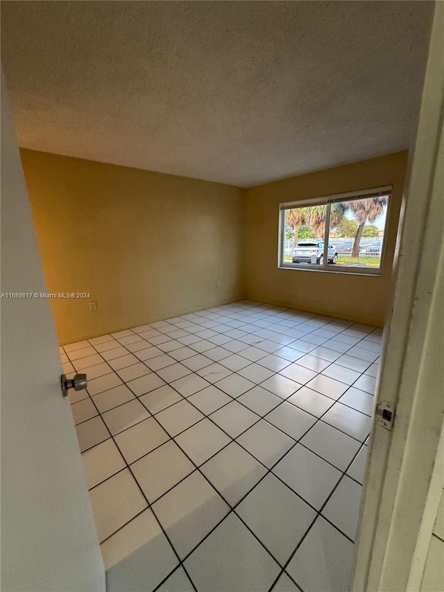 unfurnished room featuring a textured ceiling and light tile patterned floors