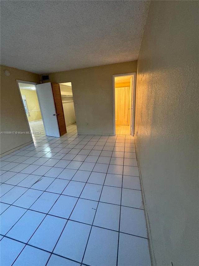 empty room featuring light tile patterned flooring and a textured ceiling