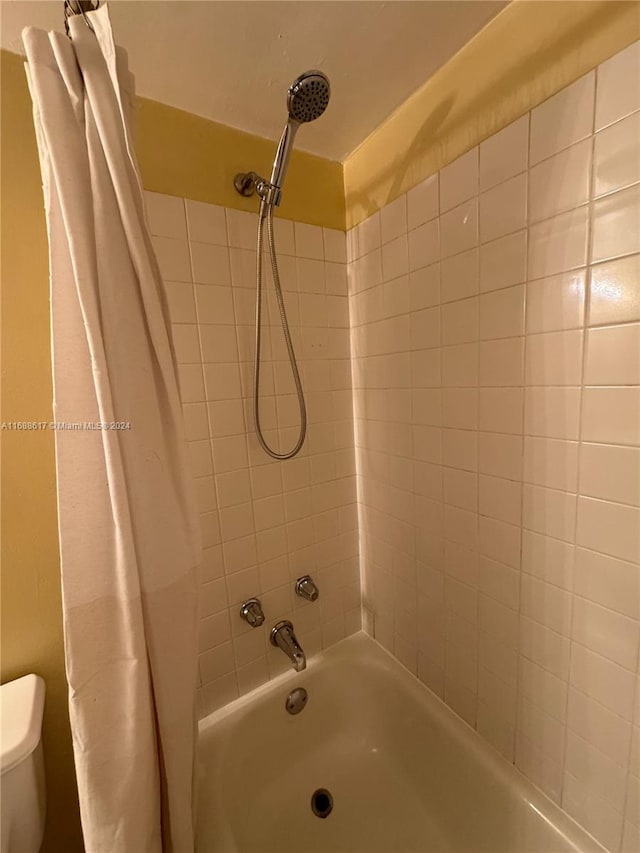 bathroom featuring shower / bath combo with shower curtain and toilet