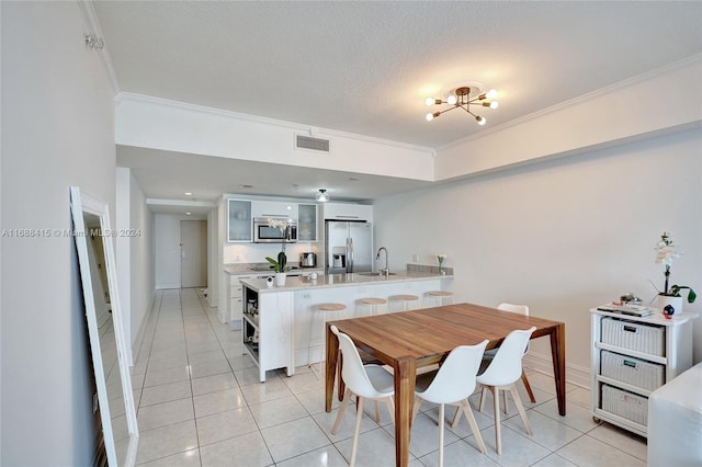 tiled dining space featuring a textured ceiling, a chandelier, sink, and crown molding