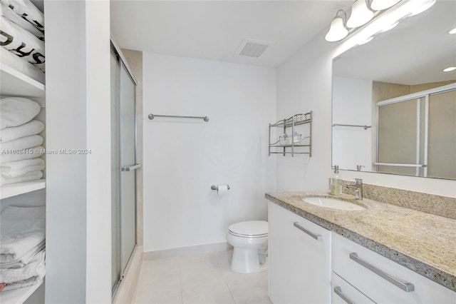 bathroom featuring vanity, tile patterned floors, toilet, and a shower with shower door