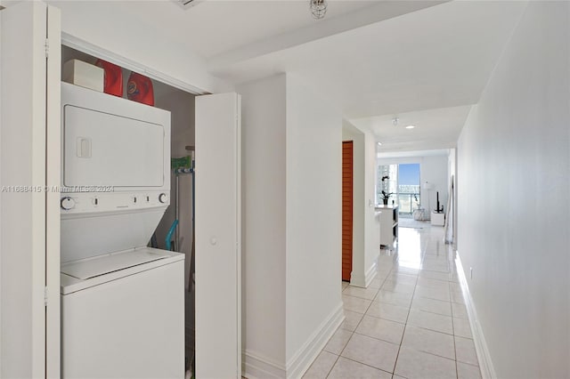 laundry area with stacked washer and clothes dryer and light tile patterned flooring