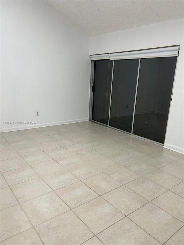 empty room featuring a textured ceiling and light tile patterned floors