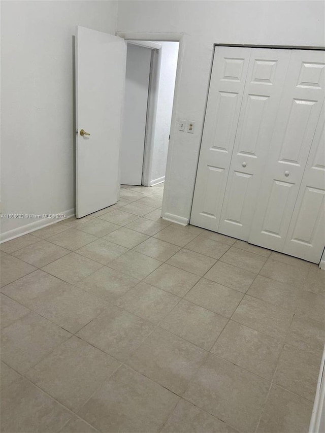 unfurnished bedroom with light tile patterned flooring and a closet