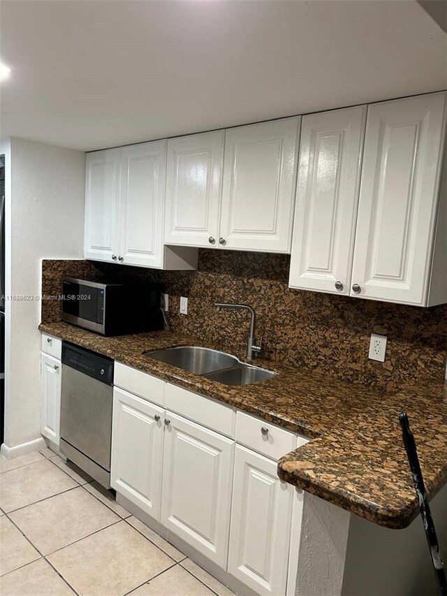 kitchen featuring stainless steel appliances, backsplash, white cabinetry, light tile patterned floors, and sink