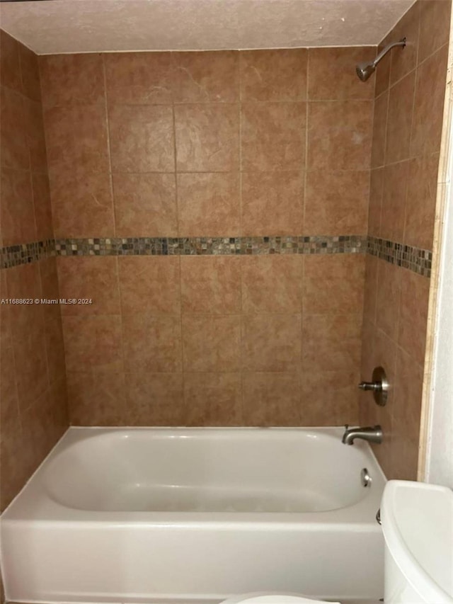 bathroom with tiled shower / bath and toilet