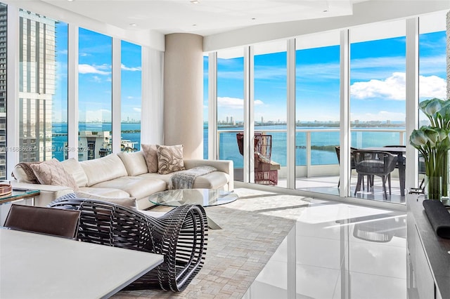 living room featuring tile patterned flooring, plenty of natural light, and a water view