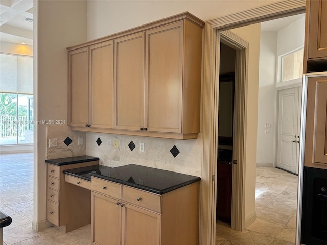 kitchen featuring dark stone countertops, tasteful backsplash, and light brown cabinetry