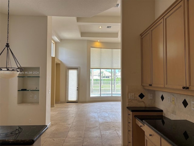 kitchen featuring pendant lighting, dark stone counters, and backsplash