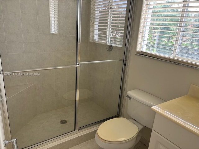 bathroom featuring toilet, vanity, walk in shower, and plenty of natural light