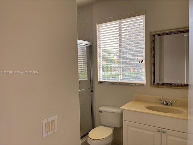 bathroom with vanity, toilet, and a shower with door