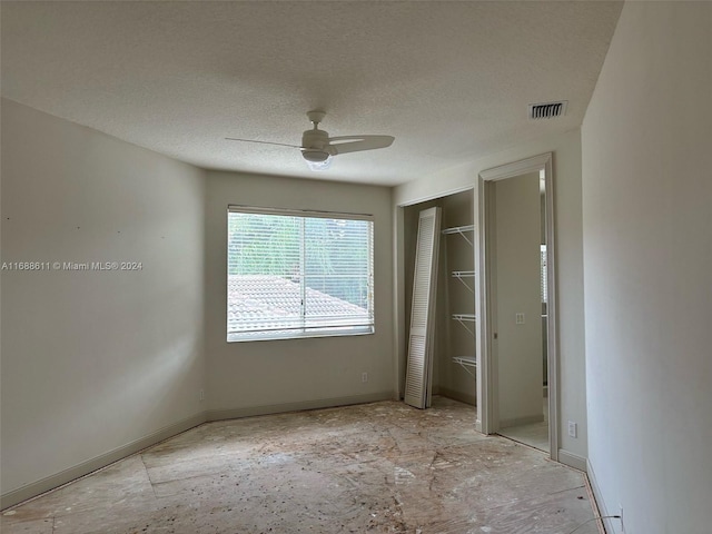 unfurnished bedroom with ceiling fan and a textured ceiling