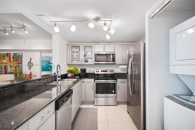 kitchen with stacked washer / dryer, white cabinetry, dark stone countertops, and stainless steel appliances