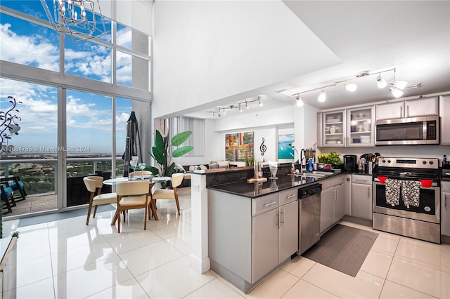 kitchen featuring stainless steel appliances, light tile patterned floors, hanging light fixtures, sink, and kitchen peninsula