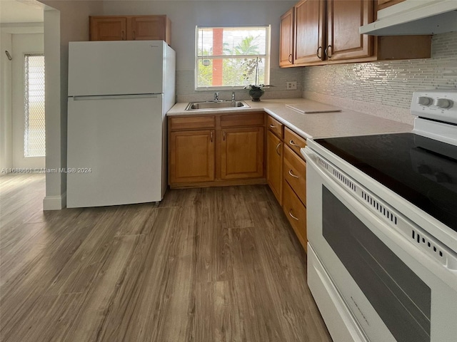 kitchen featuring hardwood / wood-style floors, white appliances, sink, and decorative backsplash