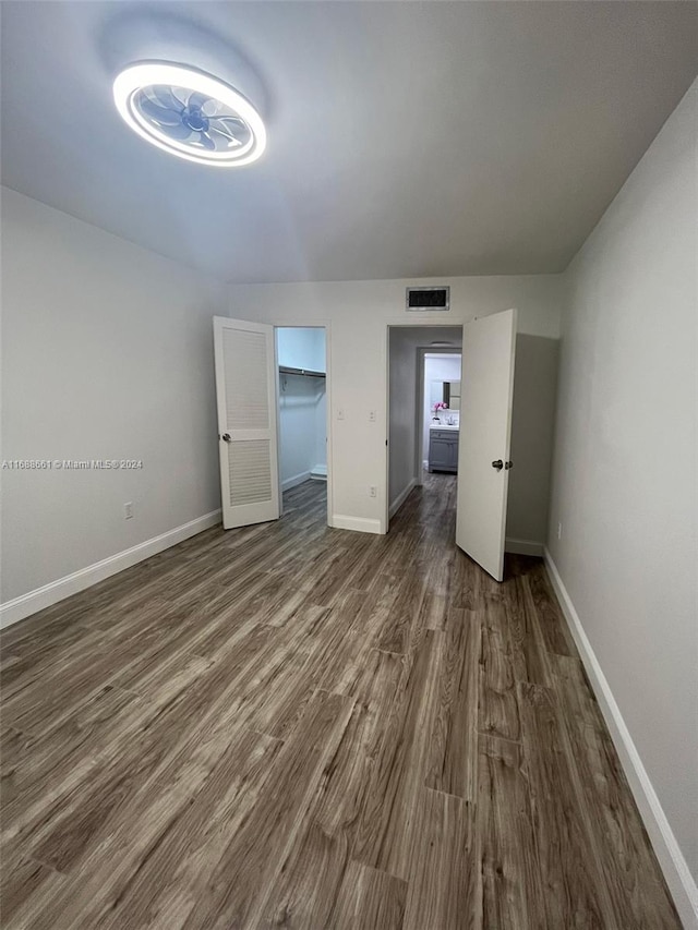 unfurnished bedroom with a spacious closet, dark hardwood / wood-style floors, and a closet