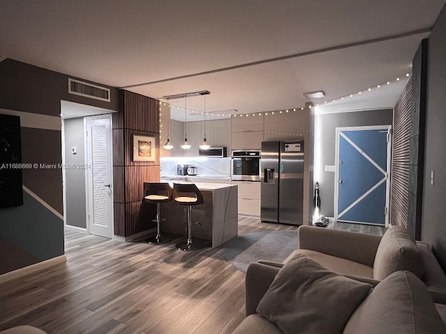 111 Golden Isles Dr Unit G5, Hallandale Beach, FL 33009 - kitchen with appliances with stainless steel finishes, wood finished floors, light countertops, a breakfast bar, and open floor plan