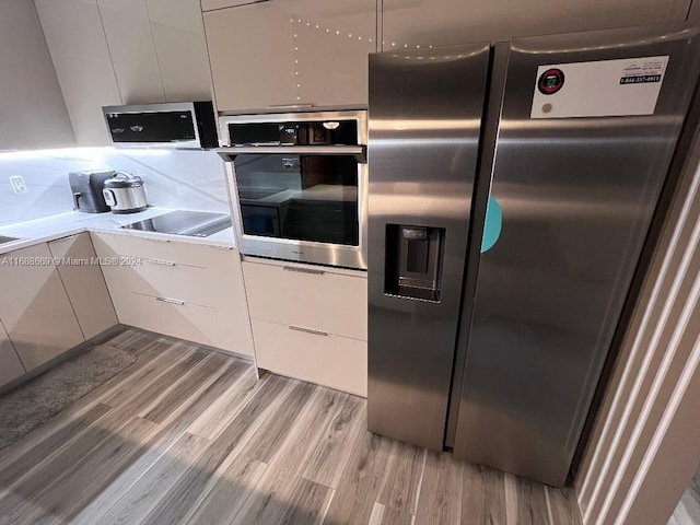 kitchen featuring stainless steel appliances, white cabinetry, and light wood-type flooring