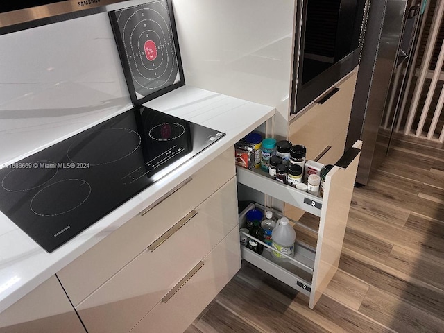 111 Golden Isles Dr Unit G5, Hallandale Beach, FL 33009 - kitchen view of dark wood finished floors, light countertops, white cabinets, and black electric cooktop