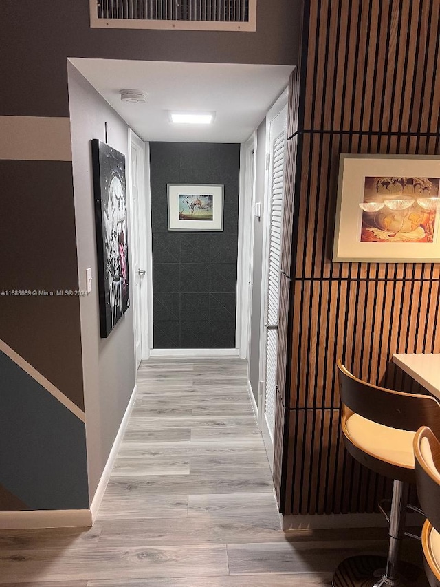 111 Golden Isles Dr Unit G5, Hallandale Beach, FL 33009 - hall featuring an accent wall and wood finished floors