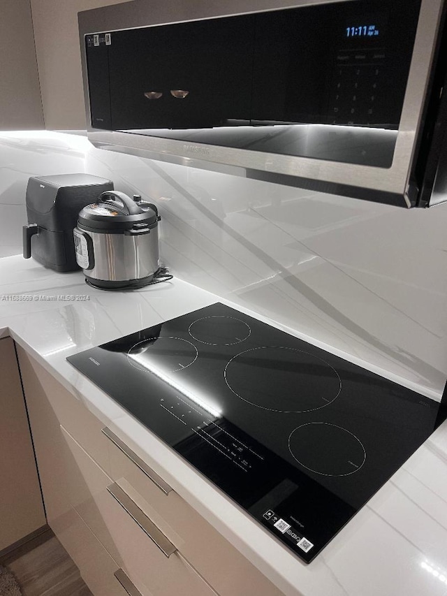 111 Golden Isles Dr Unit G5, Hallandale Beach, FL 33009 - kitchen view of black electric cooktop, stainless steel microwave, and light countertops