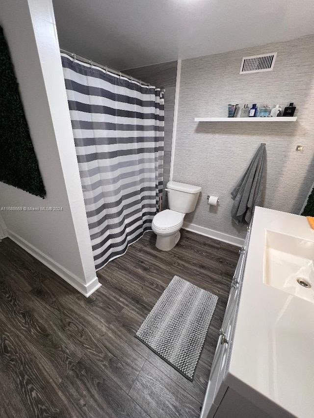 bathroom with wood-type flooring, toilet, vanity, and a shower with shower curtain