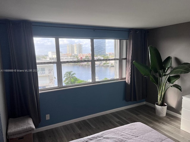 bedroom with hardwood / wood-style flooring, multiple windows, and a water view