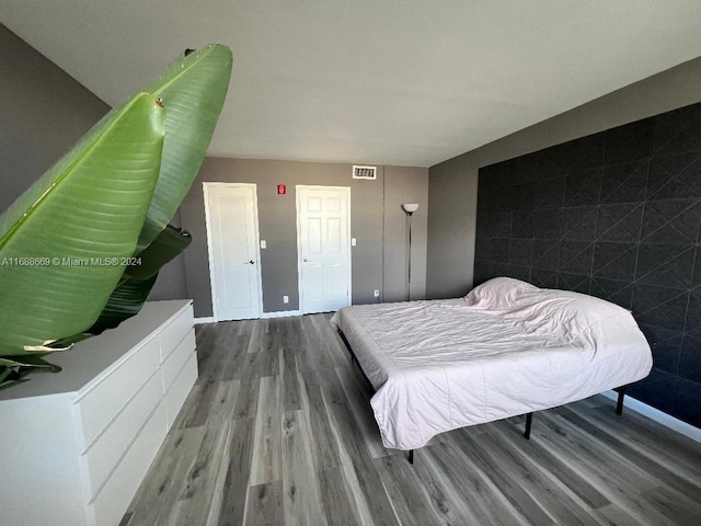 bedroom featuring hardwood / wood-style flooring and tile walls