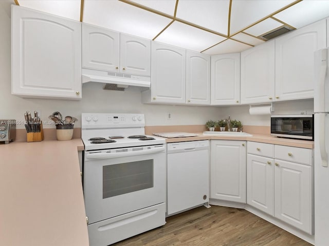 kitchen featuring white appliances, wood-type flooring, white cabinetry, and sink