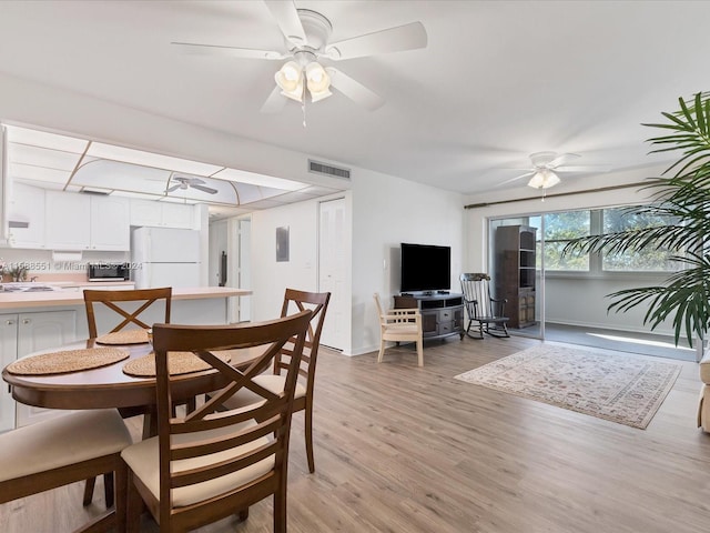 dining room with ceiling fan, sink, and light hardwood / wood-style floors