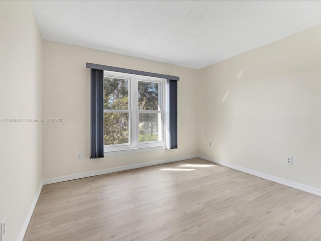 spare room featuring light hardwood / wood-style floors and a textured ceiling