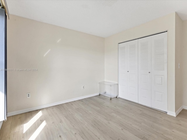 unfurnished bedroom with a closet and light hardwood / wood-style flooring