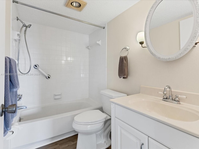 full bathroom with wood-type flooring, vanity, a textured ceiling, toilet, and tiled shower / bath