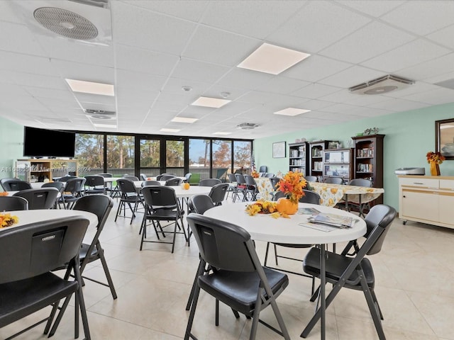 dining room featuring a drop ceiling, expansive windows, and light tile patterned floors