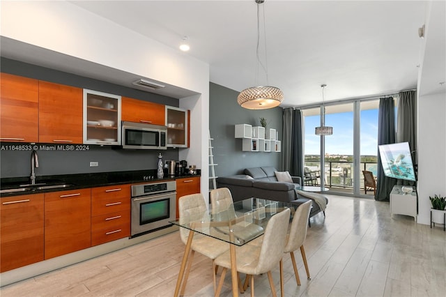 kitchen with sink, decorative light fixtures, appliances with stainless steel finishes, and light hardwood / wood-style flooring