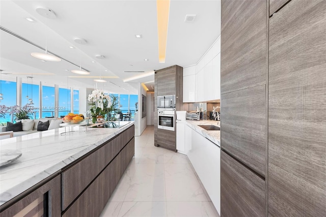 kitchen featuring white cabinets, stainless steel appliances, dark brown cabinets, and light stone counters