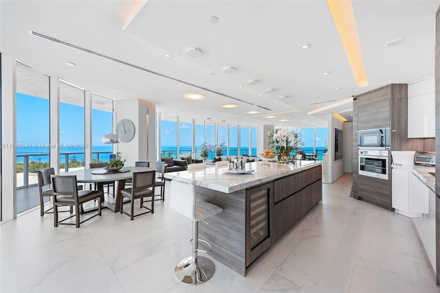 kitchen with a water view, white cabinets, a kitchen island, light stone countertops, and appliances with stainless steel finishes