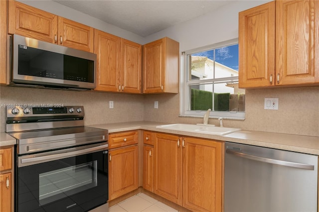 kitchen featuring a textured ceiling, appliances with stainless steel finishes, sink, and light tile patterned flooring