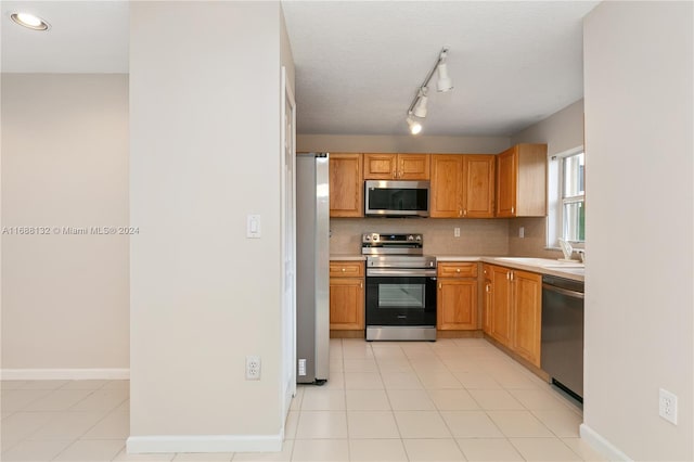 kitchen with appliances with stainless steel finishes, sink, backsplash, and light tile patterned floors