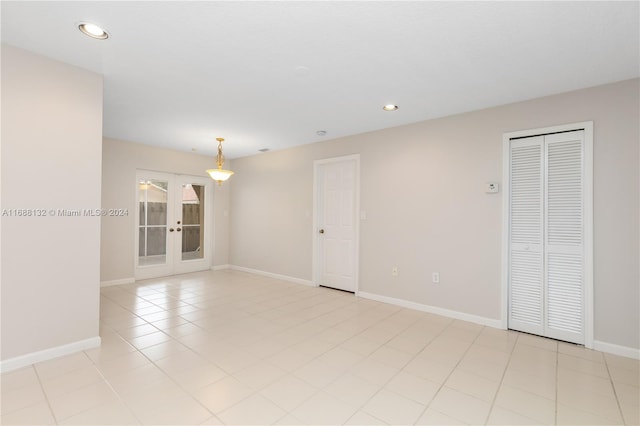 empty room featuring french doors and light tile patterned flooring