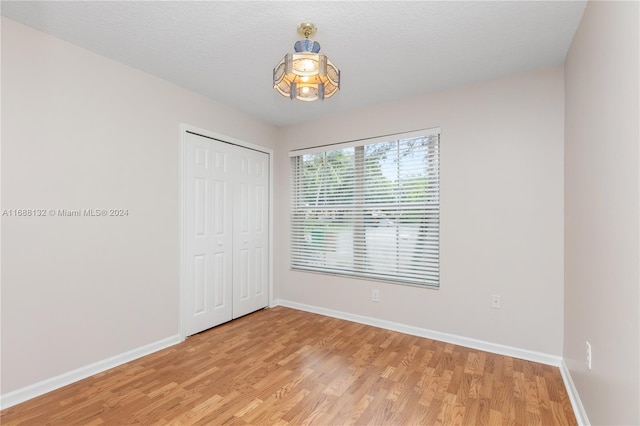 unfurnished bedroom with a closet, wood-type flooring, and a textured ceiling