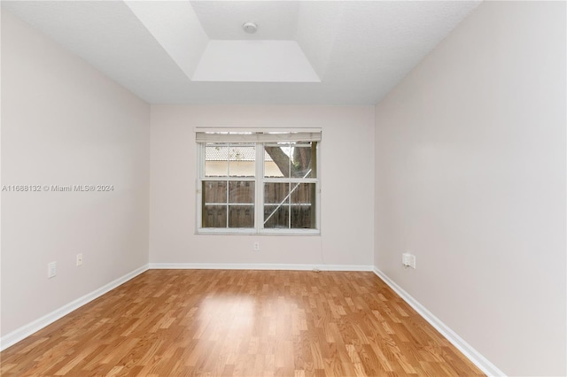 empty room with a textured ceiling, light hardwood / wood-style flooring, and a skylight