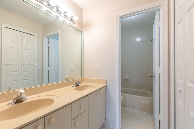 full bathroom with toilet, tiled shower / bath combo, vanity, and tile patterned floors