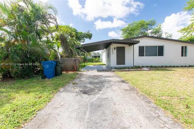 ranch-style house featuring a front lawn and a carport