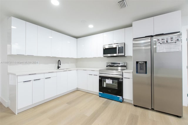 kitchen with white cabinets, light hardwood / wood-style floors, sink, and appliances with stainless steel finishes