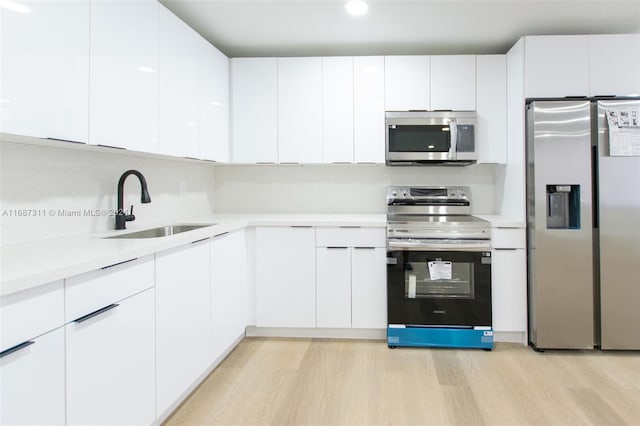 kitchen with white cabinets, light hardwood / wood-style floors, stainless steel appliances, and sink