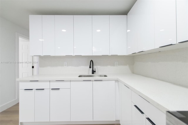 kitchen with white cabinetry, sink, and light wood-type flooring