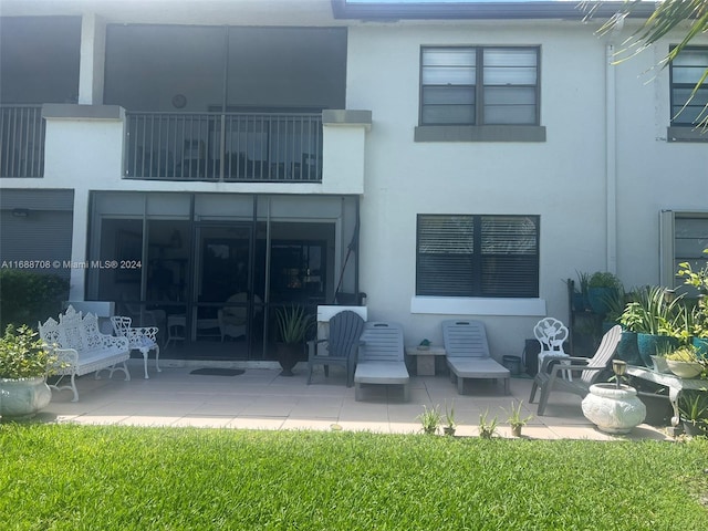 rear view of house featuring a balcony, a yard, and a patio area