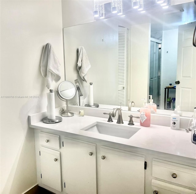 bathroom featuring a shower with door and vanity