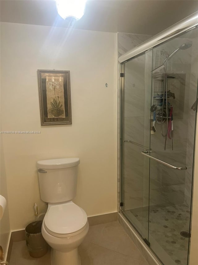 bathroom with toilet, tile patterned floors, and a shower with door